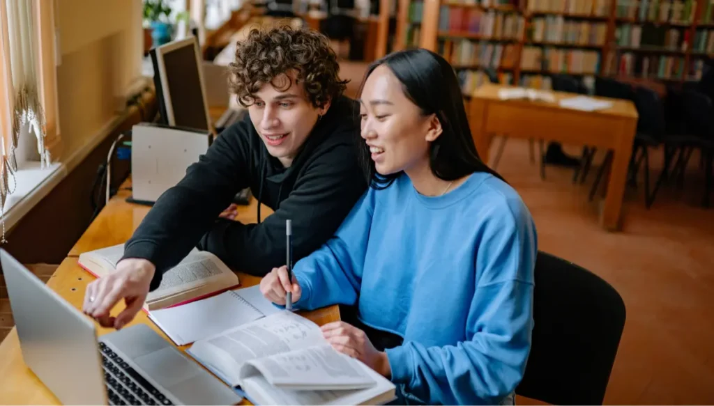 College students studying together with a Windows laptop in a library, showcasing the best Windows laptops for students in 2026 for learning, research, coding, and productivity.